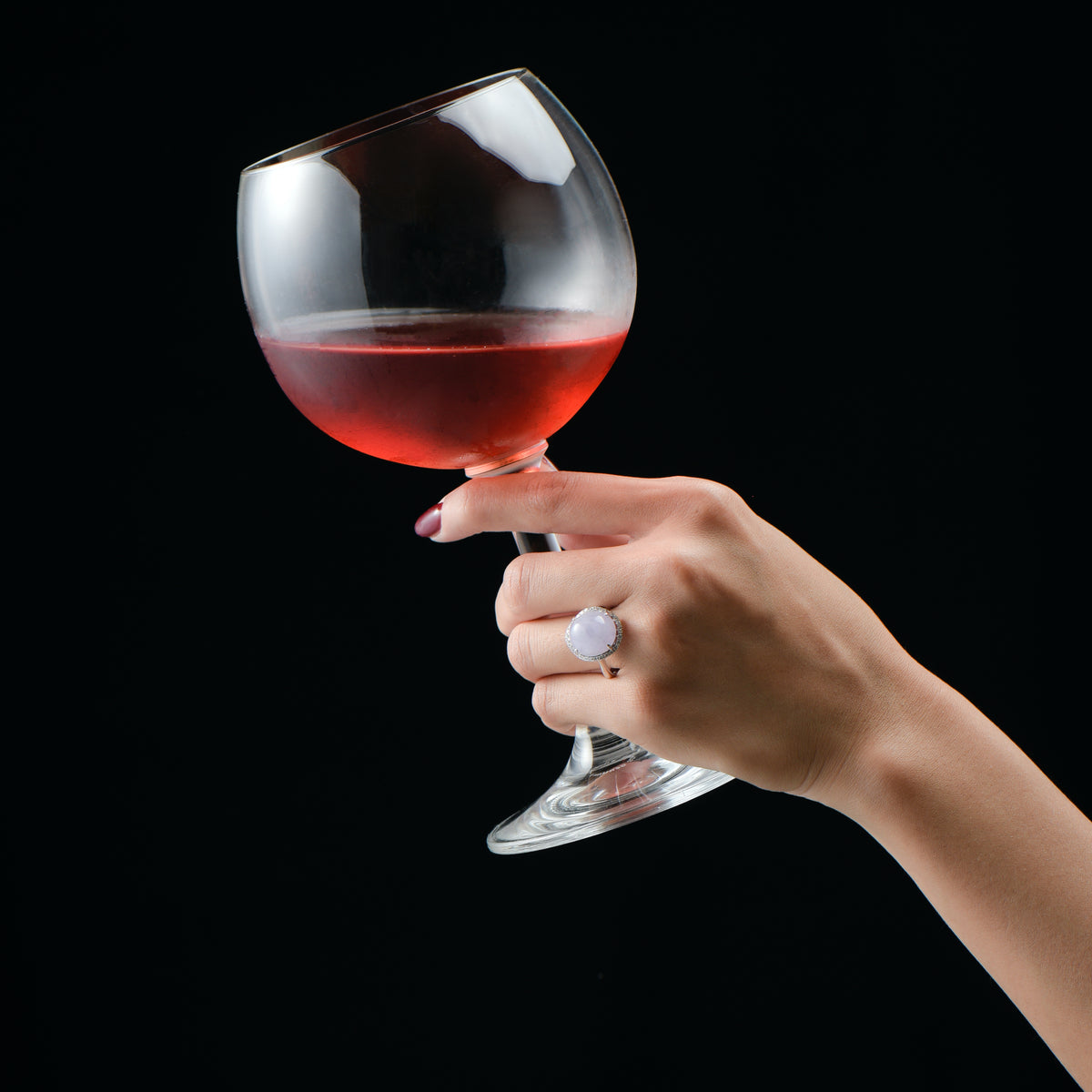 Woman holding a wine glass wearing a lavender ring