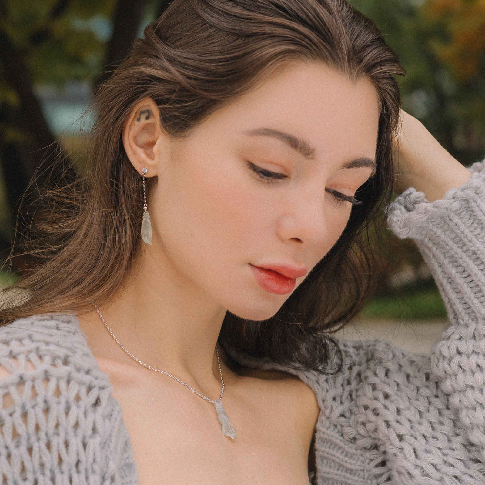 White jadeite Buddha’s hand earrings set on a white gold chain with one single stud diamond